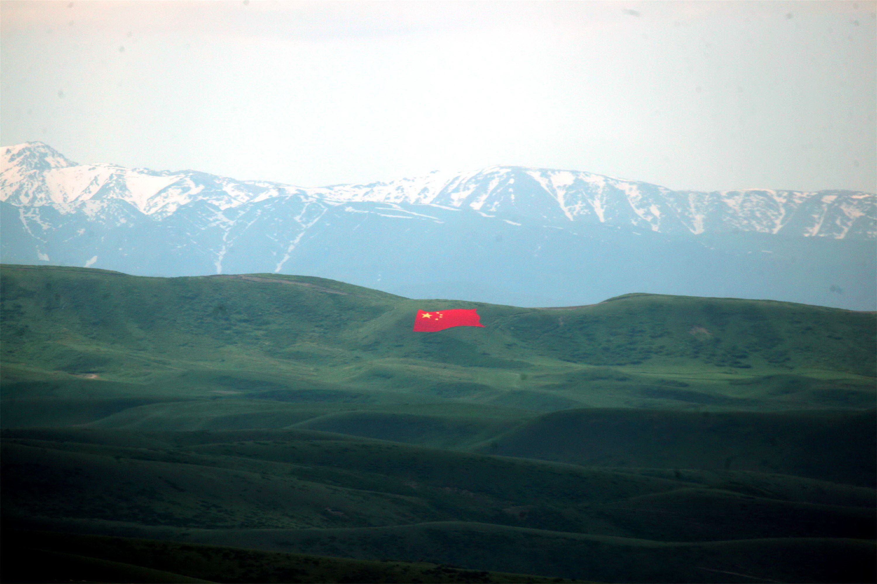 A giant national flag is displayed on the hillside of the peony valley scenic area in the Tacheng region, in northwest China, on May 13, 2019. Image by Costfoto/Barcroft Media via Getty Images. China, 2019.