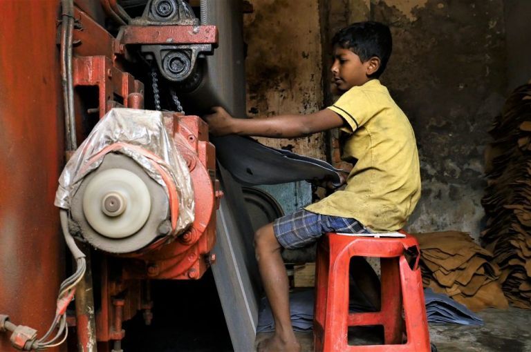 A 10-year-old boy pulls a hide from pressing machine at a tannery in Dhaka, the capital of Bangladesh. Image by Justin Kenny. Bangladesh, 2016.