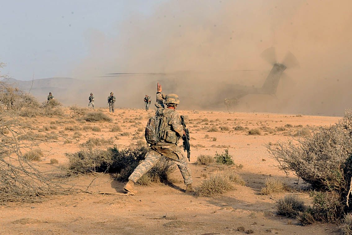 U.S. Army Sergeant Kevin Fischer, Sight Security Team 1st Battalion 161st Field Artillery, signals his security team to fill in the security perimeter, August 22, in the deserts of Djibouti. Image courtesy of the U.S. military's press photos. Djibouti, 2011.