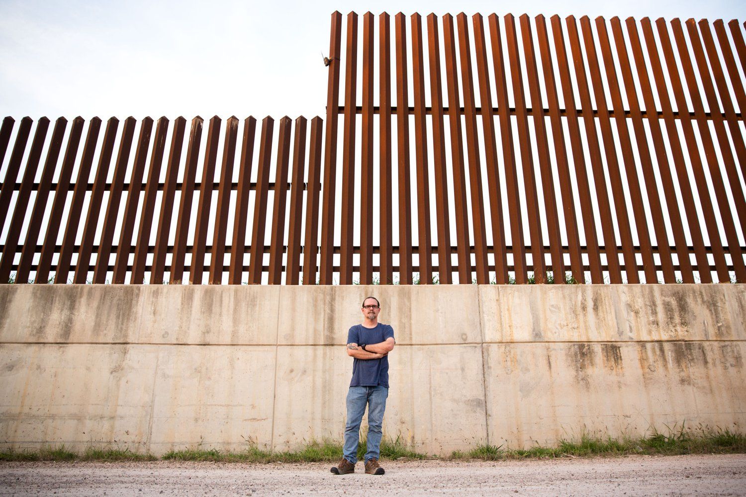 Scott Nicol, co-chair of the Sierra Club’s Borderlands Campaign, stands in front of a concrete levee topped by the border fence in Hidalgo County. Environmentalists, along with the U.S. Fish and Wildlife Service, say the barrier endangers wildlife because animals can't reach dry land during floods.  Image by Callie Richmond. United States, 2017.