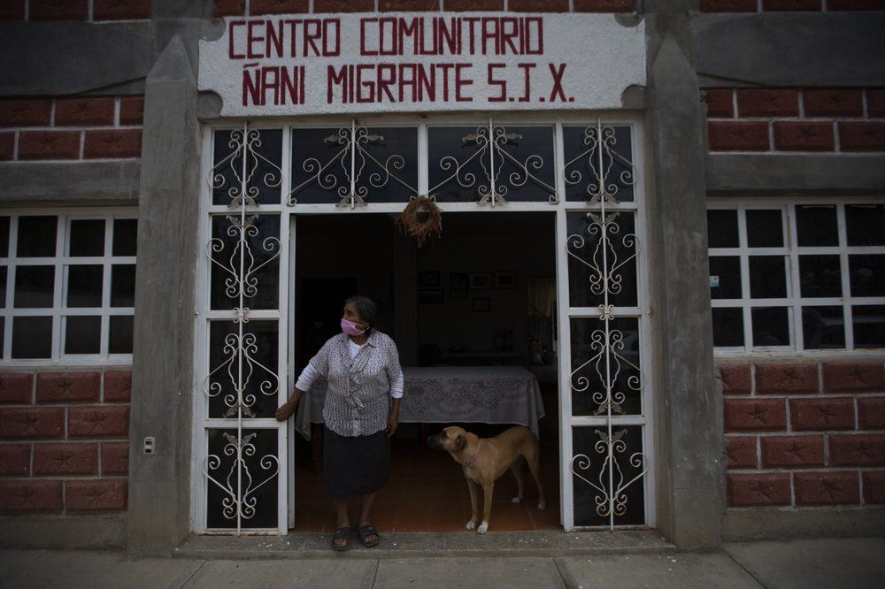 Clara Lara, whose son lives in Staten Island, New York, stands outside the home that her son built for himself and in the meantime serves as a community center while he's away, in San Jeronimo Xayacatlan, Mexico, Thursday, June 25, 2020. Image by Fernando Llano/AP Photo. Mexico, 2020.