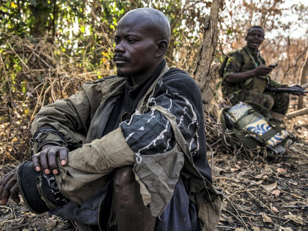 A suspected poacher rests in the shade after being arrested, waiting to be taken to a holding cell. Constant - a father-of-one in his late 30s whose wife is pregnant with their second child - said hunting was the only way he could make ends meet for his family: “There are no opportunities. I do this to survive.” People living around the Chinko reserve are among the most marginalised and impoverished communities in the world. Image by Jack Losh. Central African Republic, 2018.
