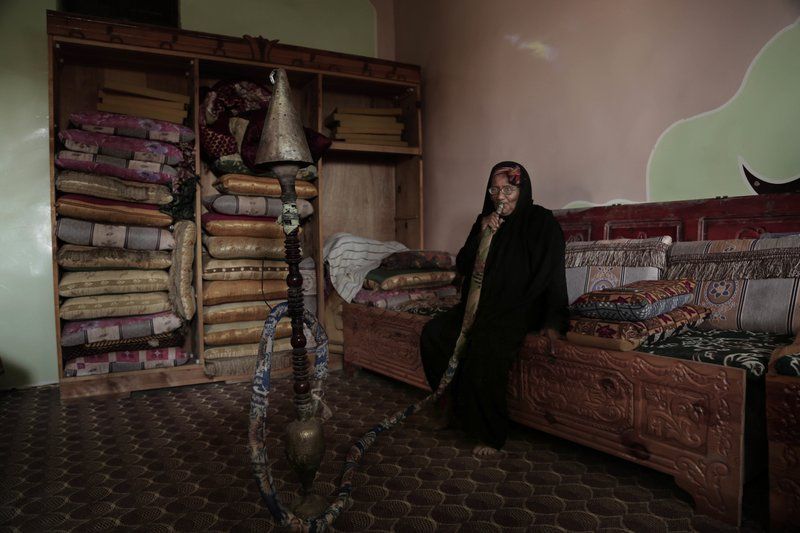 In this Feb. 12, 2018, photo, an elderly woman smokes a water pipe at the home of Ahmed al-Kawkabani, leader of the southern resistance unit in Hodeida, in al-Khoukha, Yemen. Image by Nariman El-Mofty. Yemen, 2018. 

