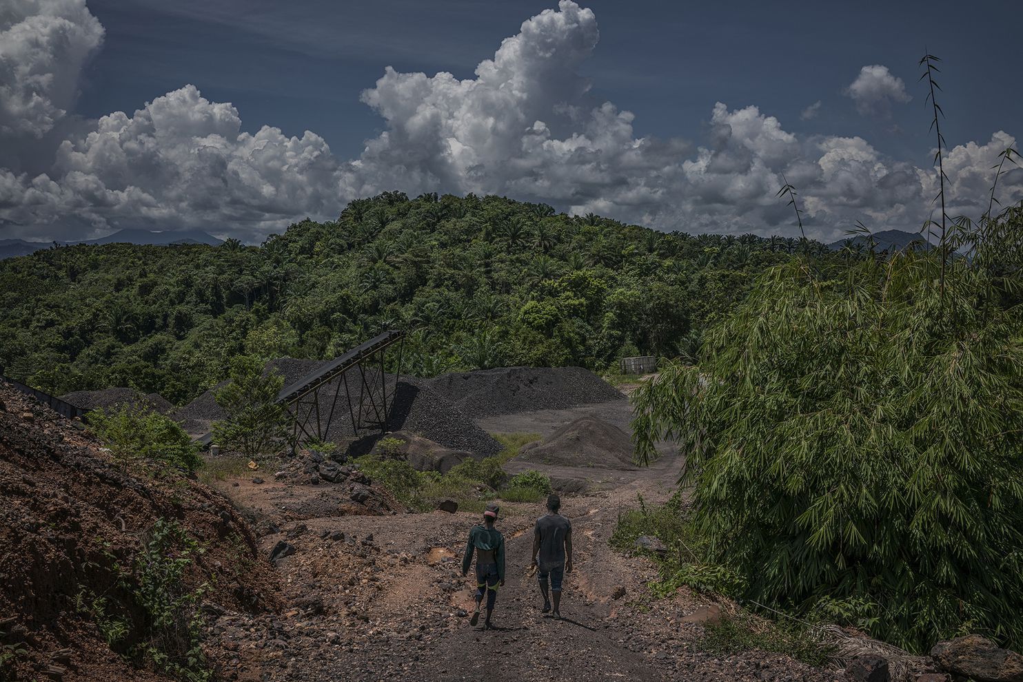 Hassan, left, and Li walk through the manganese mine processing area right above their Kuala Koh settlement. Image by James Whitlow Delano. Malaysia, 2019.