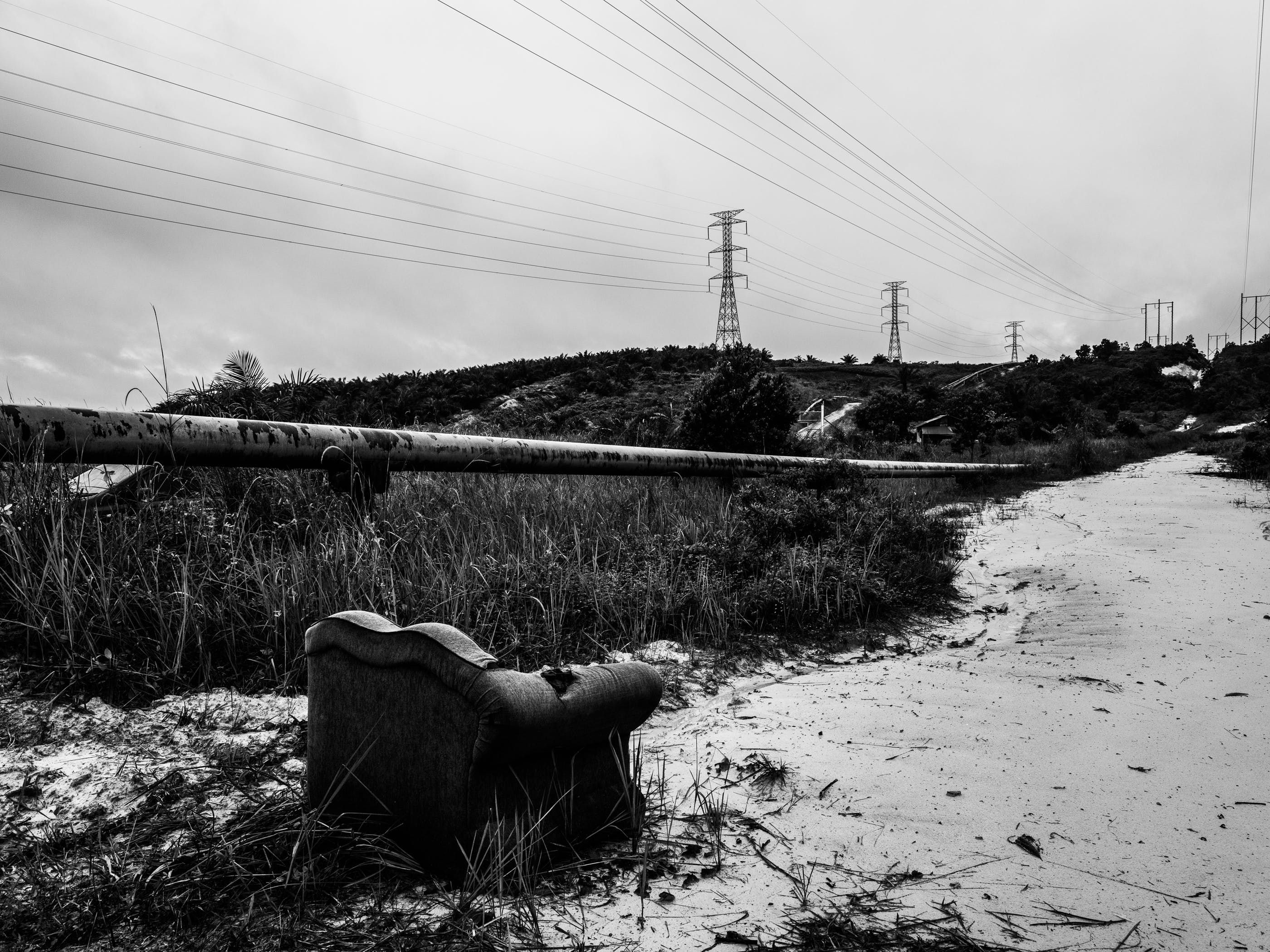 A pipeline carries fossil fuels—another kind of crude—alongside a road in Kandis. Image by Xyza Cruz Bacani. Indonesia, 2018.
