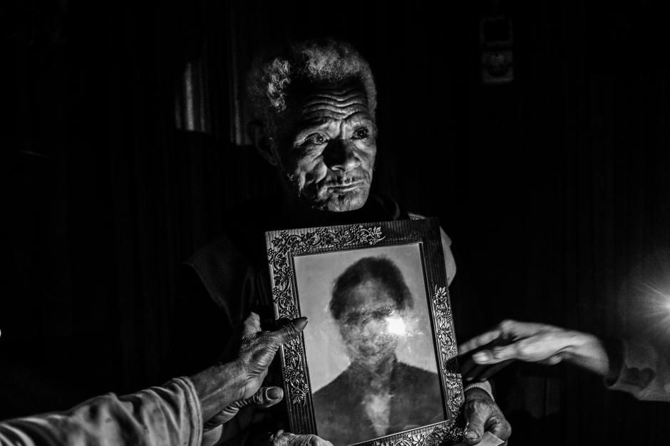 Martin Sauk shows a photo of his daughter Adelina Sauk, who was trafficked and later died in Malaysia. Image by Xyza Bacani. Indonesia, 2018.