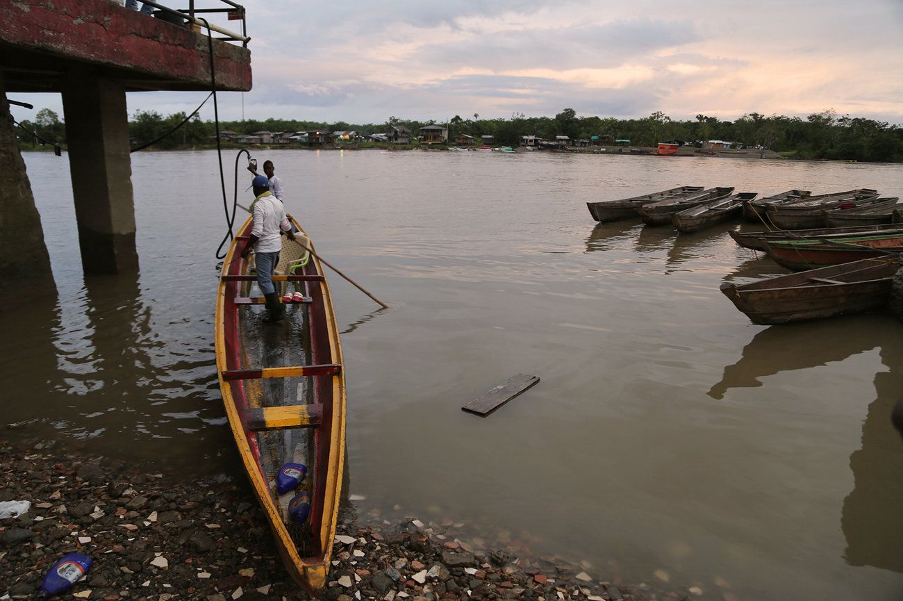 Men in the city of Quibdó prepare the motorboat they use to make the hours-long river journey to a cacao community. Most Chocó farmers live in riverside communities far from Quibdó and must travel there to sell their crops — by motorboat, because the villages lack roads. Image by Verónica Zaragovia. Colombia, 2018.