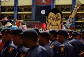 Law enforcement officers in front of an effigy of President Rodrigo Duterte during a rally against the extrajudicial killings and other issues in Quezon City, July 24, 2017. Image by Pat Nabong. Philippines, 2017.