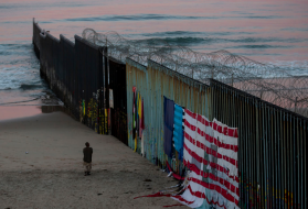 In Tijuana, a man walks at sunrise along the border fence where it meets the Pacific Ocean. Image by Erika Schultz. Mexico, 2019.