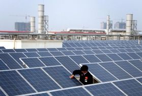 A worker cleans a solar panel on top of a factory building in Baoding City. China is installing a soccer field's worth of solar panels every hour. Image by Sean Gallagher. China, 2017.