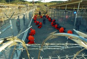 Guantánamo Bay detainees sit in a holding area at Camp X-Ray on January 11, 2002. Image courtesy of the Pentagon by Shane T. McCoy.
