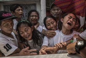 Pedro Abletes, on the far left, comforts his wife, as they say their final good-byes to their son, Junmar. Image by James Whitlow Delano. Philippines, 2017.