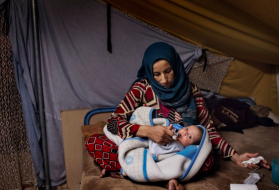 Illham holds her seven week-old baby Faraj in her tent on Nov. 20. Image by Lynsey Addario for TIME. Greece, 2016.