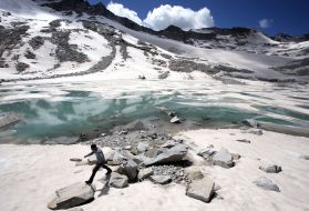 A man walks over rocks near to a glacial lake that has formed at the base of the Dagu Glacier on the southeast edge of the Tibetan Plateau. The glacier has been reducing in size in recent years as a result of rising temperatures in the region. Image by Sean Gallagher. China, 2012.