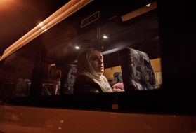 After an exhausting day-long flight, Syrian refugee Taimaa Abazli takes a bus from Talinn, Estonia, to her new home in rural Polva, a village of 6000 people. Photo by Lynsey Addario. Estonia, 2017.