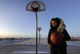 In this Feb. 17, 2019, photo, Deidre Levi carries her basketball as she walks to work in the Native Village of St. Michael, Alaska. Levi says she spoke up about being sexually assaulted because she wanted to be a role model for girls in Alaska. Image by Wong Maye-E/Associated Press. United States, 2019.


